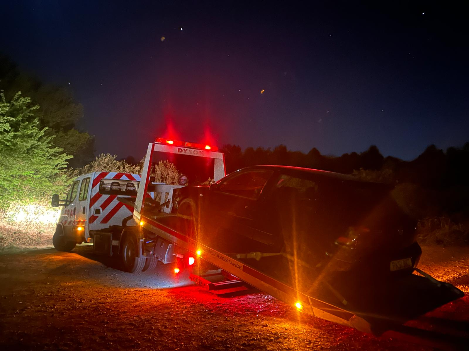 Recovery truck at night loading a car